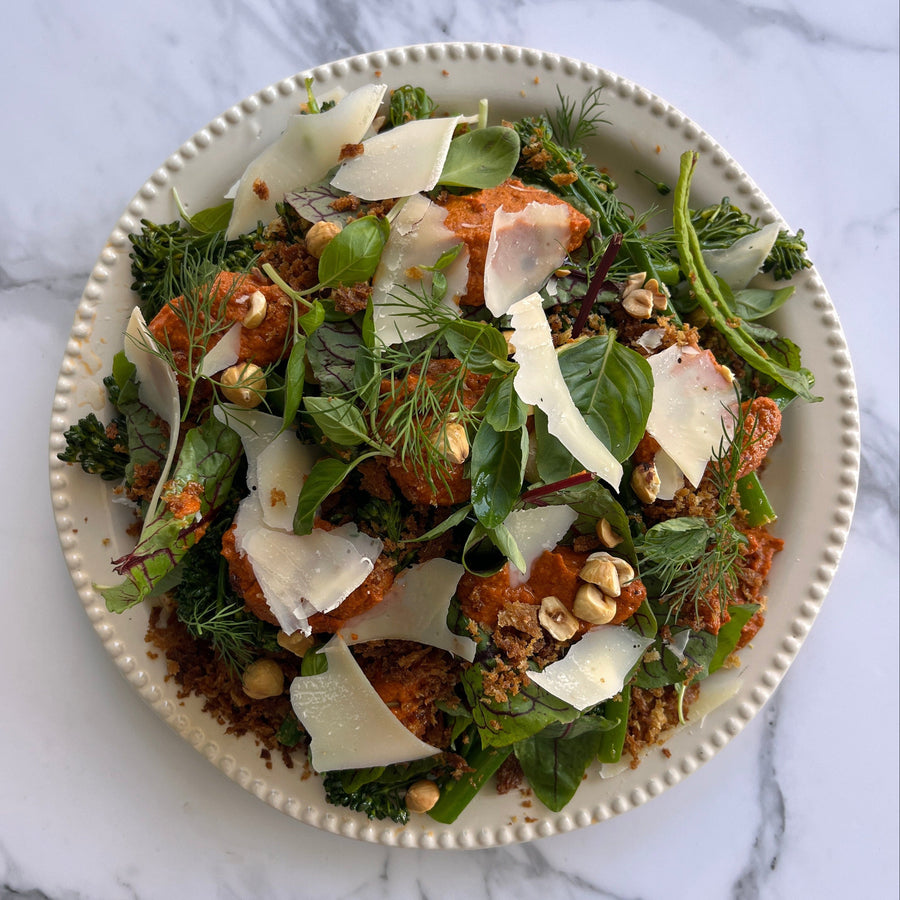 Salad with greens, nuts, and cheese on a marble surface