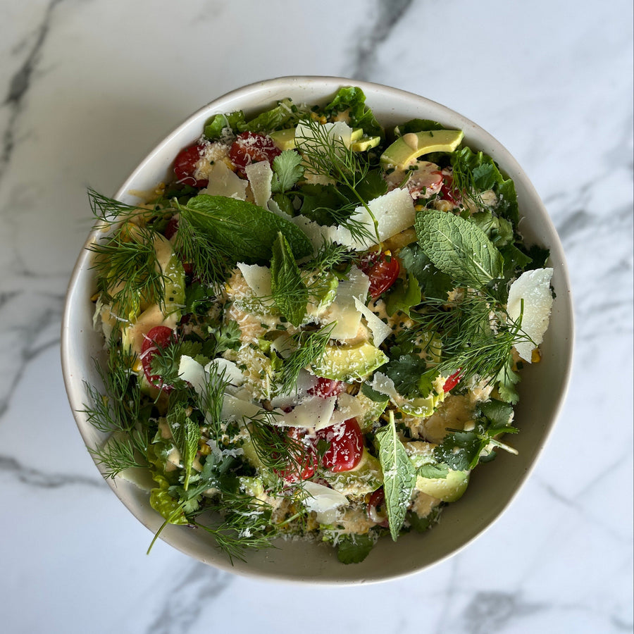 Bowl of corn and baby gem salad  on a marble surface