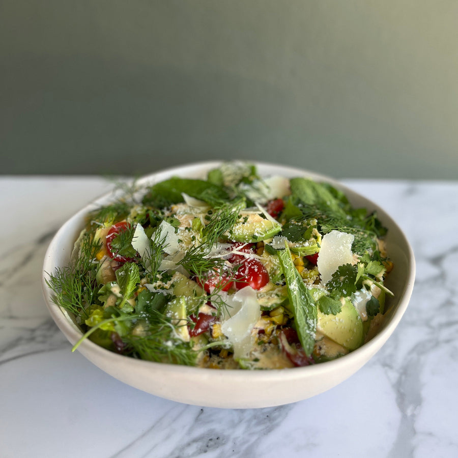 Bowl of corn, avocado, baby gem and tomatoes salad a marble surface with a neutral background
