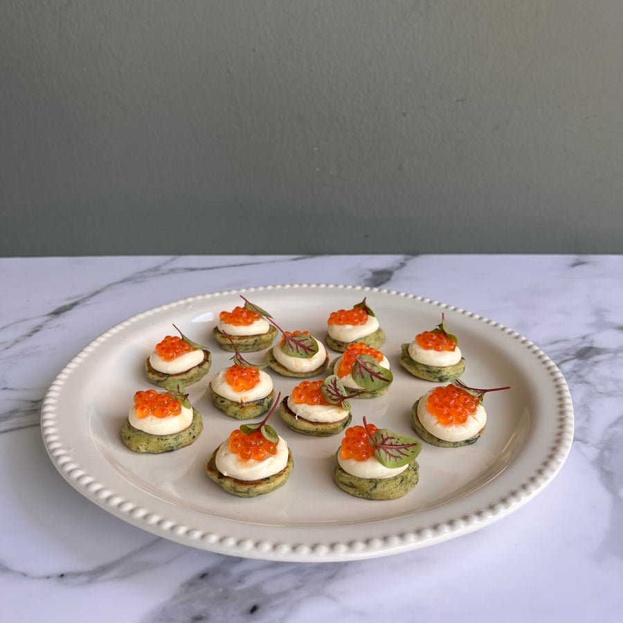 Platter of Elegant canapes blinis topped with chive, horseradish crème fraîche and premium Yarra
Valley salmon caviar on a marble surface