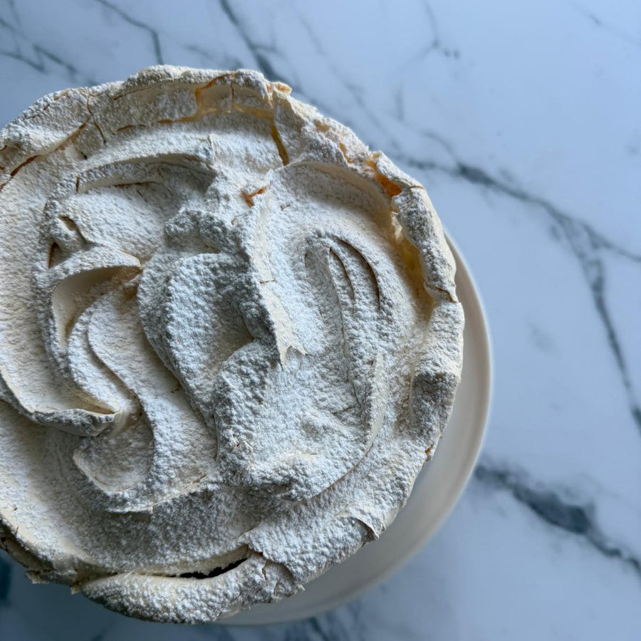 Revisited summer pudding sponge  topped with swirls of baked merigne and dusted icing sugar on a marbel background