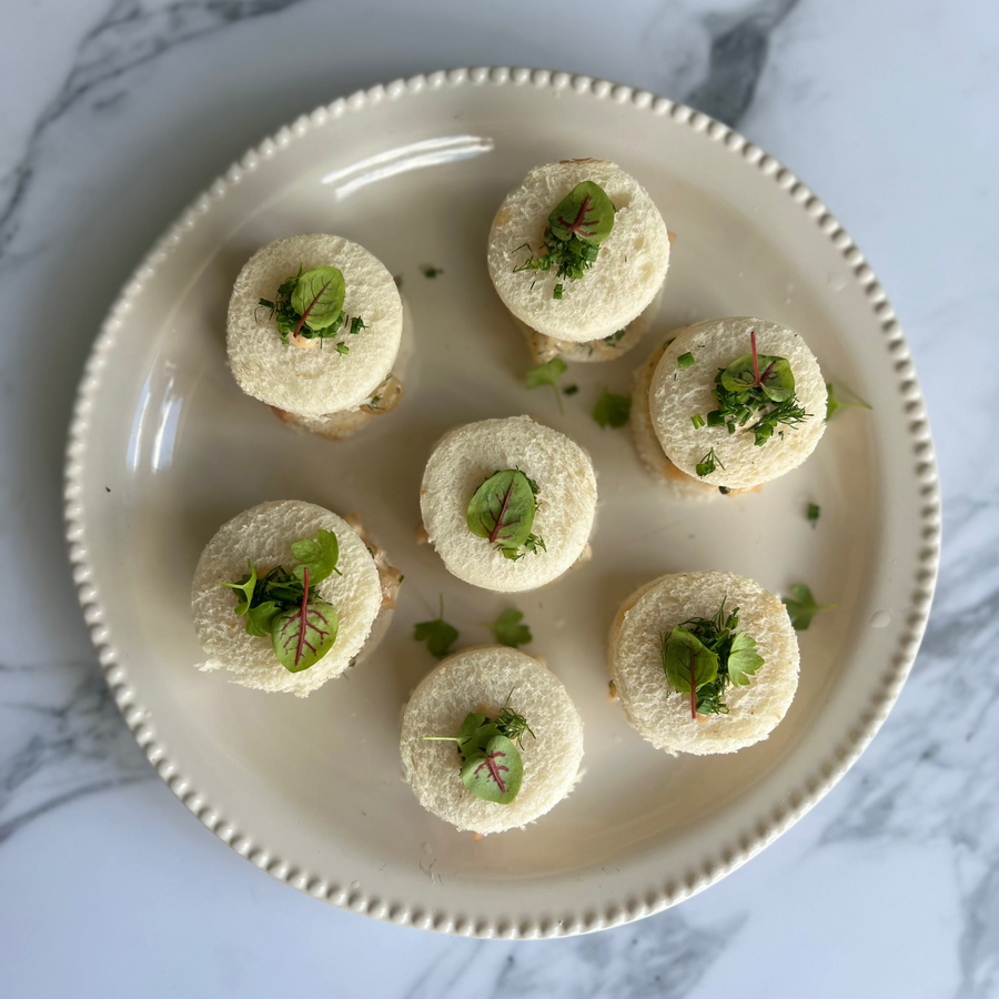 Platter of small christmas appetizers with prawn cocktail sandwiched with a leaf of read sorrel on top on a marble surface