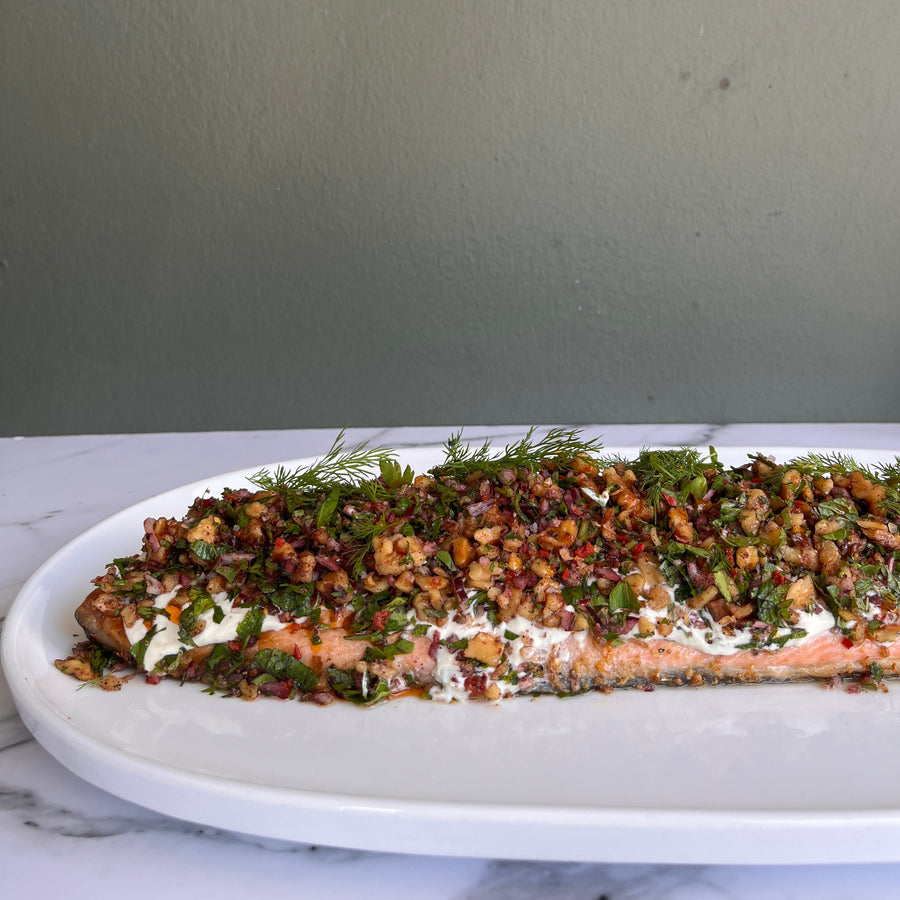 Plated salmon fillet, with tahini yoghurt and a festive walnut
tarrator on a neutral background.