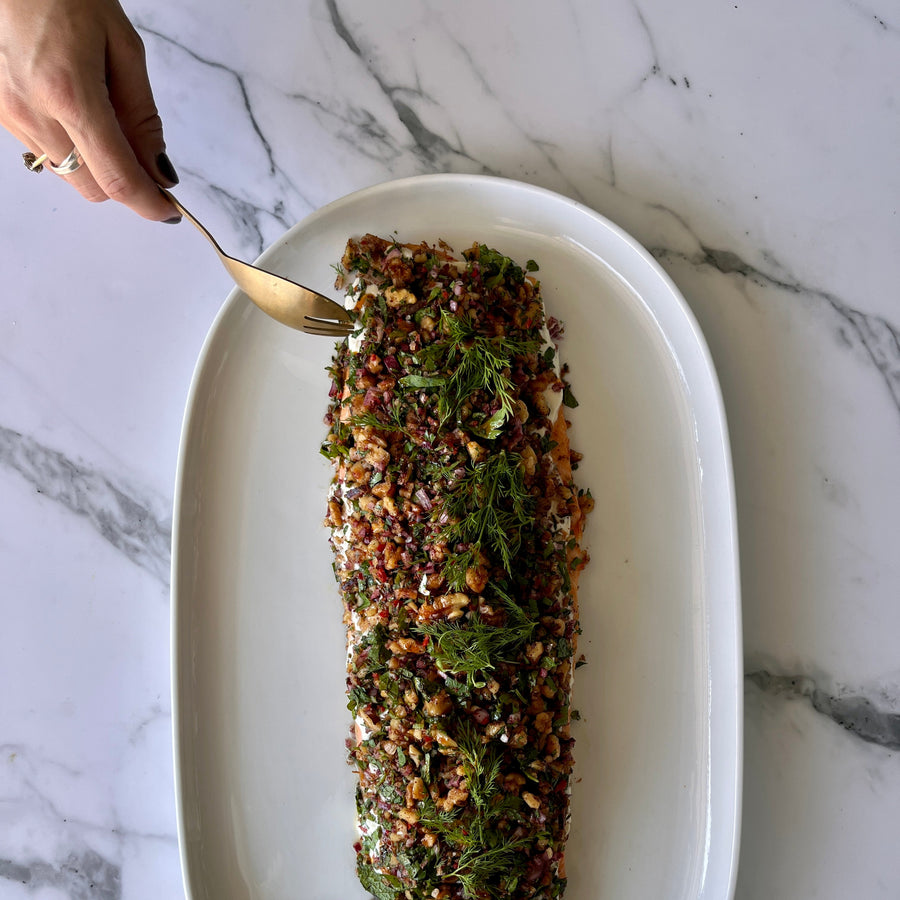 Plated Roasted Salmon Fillet topped with tahini yoghurt and a festive walnut
tarrator on a marble surface