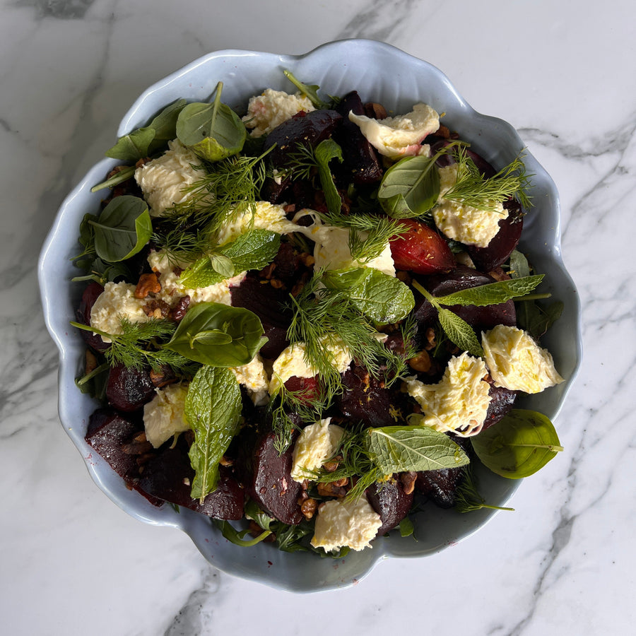 Salad with roasted beetroot and blood orange salad with spiced walnuts and straciatella in a blue bowl on a marble surface