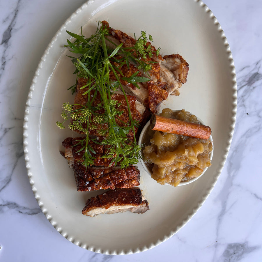 Plated dish with slow roasted pork belly and apple chutney on a marble surface