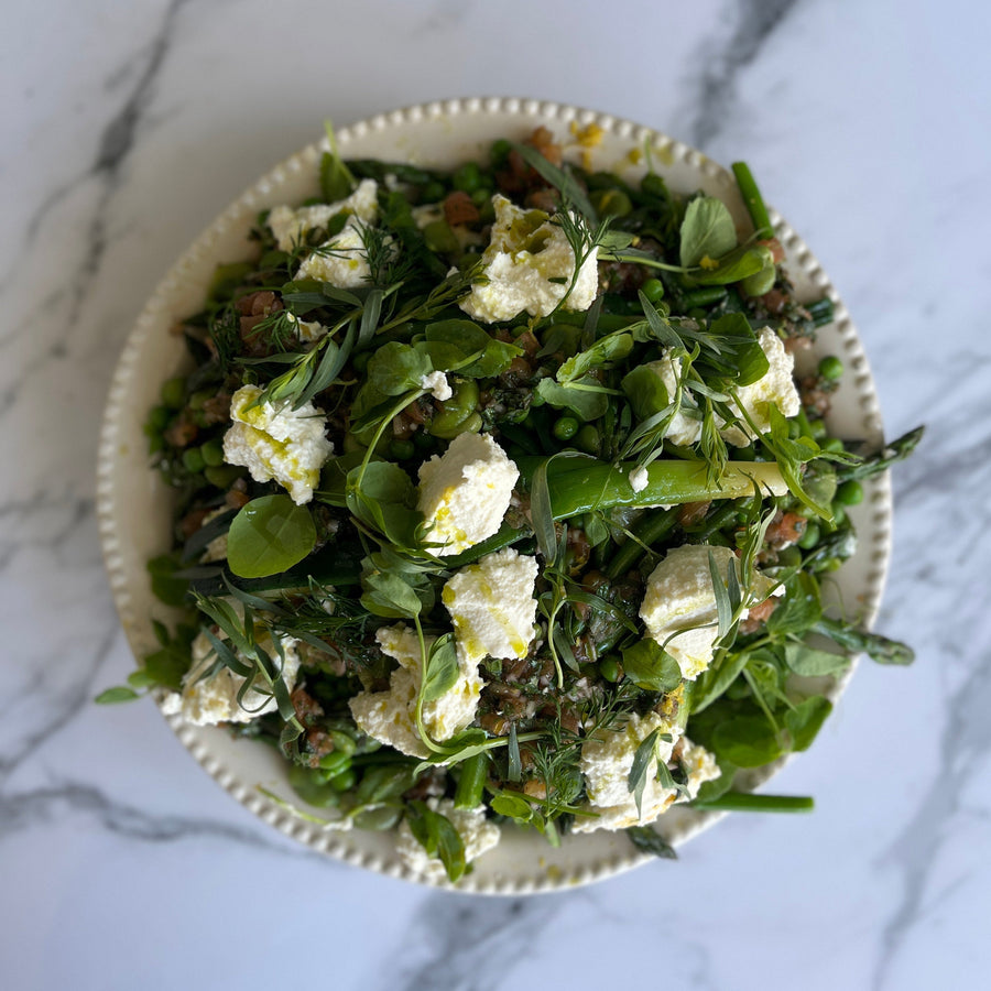 Bowl of green salad with ricotta cheese on a marble surface